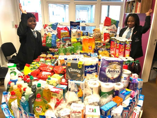 Two students standing either side of a large table full of food and provisions