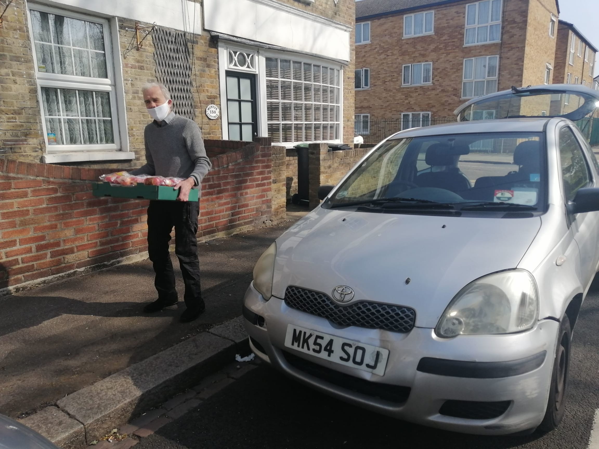 Volunteer taking food delivery from car and delivering to a vulnerable person