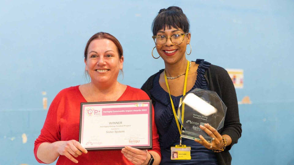Okela Douglas (right) receiving the Haringey Giving Funded Project of the Year Award 2022 from Helen Rayfield, Chair of Haringey Giving (left)